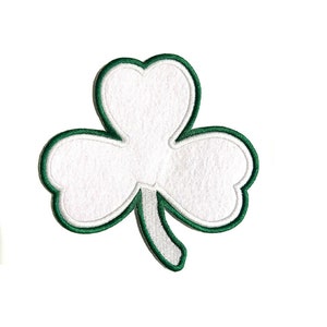 May include: A white shamrock patch with a green border and stem. The three-leaf clover design is embroidered with a white center and a green outline, perfect for St. Patrick's Day or Irish-themed crafts.