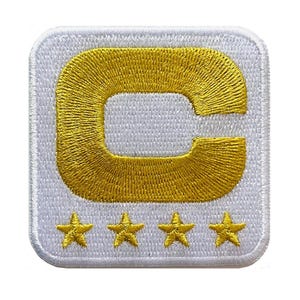 May include: Embroidered patch with a gold letter "C" and four gold stars on a white background. The patch is square with rounded corners and a stitched border. The design is likely for clothing or accessories.