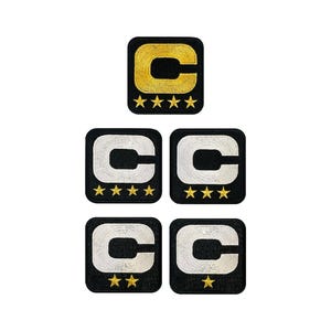 May include: A selection of embroidered patches. Each patch is square and black, featuring a capital letter "C" in gold or silver, with gold stars below. The top patch has a gold "C" and four stars.