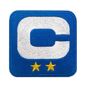 May include: A blue embroidered patch featuring a white "C" design and two yellow stars. The patch is square with rounded corners and a blue border. The design is centered on a white background.