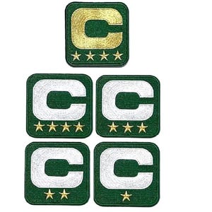 Puede incluir: Cinco parches bordados con un fondo verde con una letra "C" blanca o dorada y estrellas doradas. El parche superior tiene una "C" dorada y cinco estrellas. Los otros cuatro parches tienen una "C" blanca y cuatro estrellas.