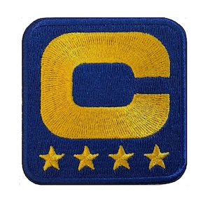 May include: Embroidered patch featuring a blue background with a gold 'C' inside a square. Three gold stars are below the 'C'. The patch has rounded corners and a textured finish.