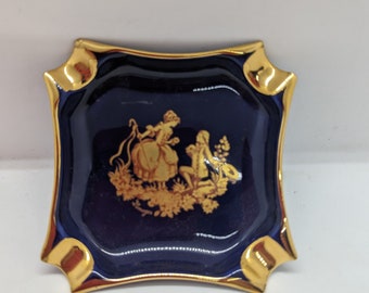 Limoges ashtray. This ashtray is cobalt blue with gold trim and an applique of a man cording a woman. The woman looks like a shepherd.