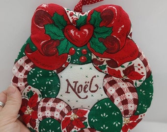 Christmas wreath from a pattern that's been stitched together by hand and stuffed. Nice Christmas colors with Noel in the middle.