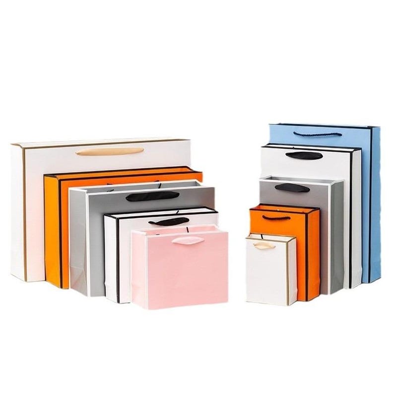 May include: A set of nine paper gift bags in various sizes and colors, including white, orange, gray, pink, and blue. The bags have black and white trim and some have gold accents.