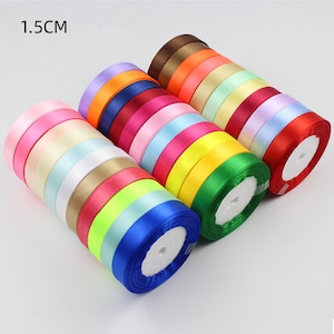 Puede incluir: Una colección de carretes de cinta de satén de 1,5 cm de ancho en varios colores, incluidos rosa, amarillo, verde, azul y rojo.