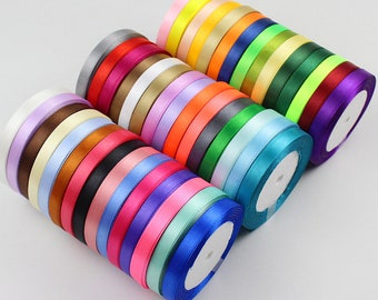 May include: Assortment of 25 spools of 1 cm wide satin ribbon in various colors, including red, blue, green, yellow, and purple. The ribbon is wound around spools with white centers.