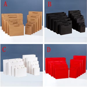 May include: Set of 10 paper gift bags in four colors: brown, black, white, and red. The bags are arranged in size order from largest to smallest.