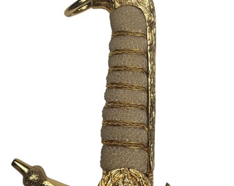 May include: A gold-coloured sword hilt with a lion head pommel, a white leather grip, and a gold-coloured guard with a decorative emblem.