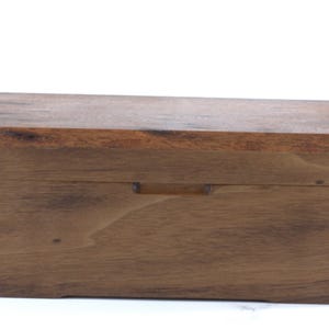 May include: A rectangular wooden box with a dark brown finish. The box has a lighter brown lid and a small handle on the front. The corners of the box are joined with visible dovetail joints.