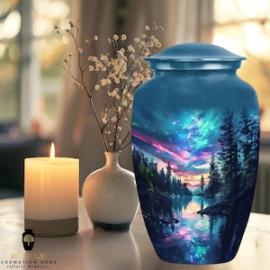 Peut inclure: Une urne funéraire bleue avec une image colorée d'un ciel étoilé nocturne reflété dans un lac entouré d'arbres.