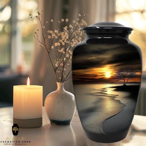 May include: A black cremation urn with a sunset scene featuring a tree on a beach. The urn has a glossy finish and a matching lid. A lit candle, a small vase with flowers, and the text "AIPLE Cremation Urns Infinite Memories" are also visible.