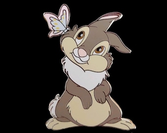 Peut inclure: Un lapin brun et beige avec un papillon rose sur l'oreille. Le lapin sourit et a une poitrine blanche et moelleuse.