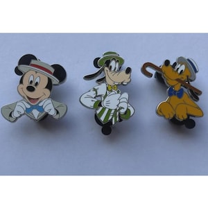 May include: Three Disney character pins: Mickey Mouse, Goofy, and Pluto. Mickey wears a hat and bow tie. Goofy is in a green hat and striped vest. Pluto holds a cane and wears a blue bow tie. All are colorful enamel pins.