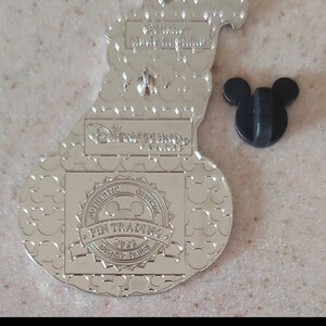 May include: Silver-toned metal pin featuring a cartoon pumpkin with a Mickey Mouse face. The back of the pin has a Mickey Mouse head pin back, a "Disneyland Resort" logo, and an "Authentic Official Pin Trading 2022 Disney Parks" label. The pin is approximately 2 3/8 inches tall and 1 5/8 inches wide.