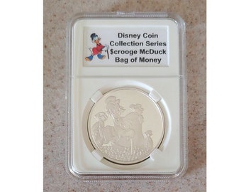 Può includere: Una moneta d'argento della serie Disney Coin Collection, con Paperon de' Paperoni e la scritta "Bag of Money". La moneta è racchiusa in un supporto protettivo trasparente. La parte superiore del supporto presenta un'immagine di Paperon de' Paperoni.