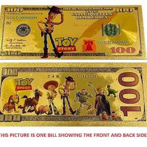 K&ouml;nnte beinhalten: Ein goldfarbener Papier-Geldschein mit Figuren aus der Toy Story-Reihe. Die Vorderseite des Scheins zeigt Woody, die R&uuml;ckseite zeigt Woody, Buzz Lightyear, Jessie und andere Figuren. Der Schein tr&auml;gt die Aufschrift "Toy Story" und "24K Gold".
