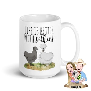 May include: White ceramic mug with a black handle featuring the text "LIFE IS BETTER WITH silkies" above an illustration of two Silkie chickens. One chicken is black, the other is white. A cartoon couple and dog are in the lower right corner.