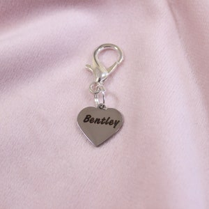 Bright silver engraved heart charm on dark bridle strap, featuring custom text for horse tack personalization.