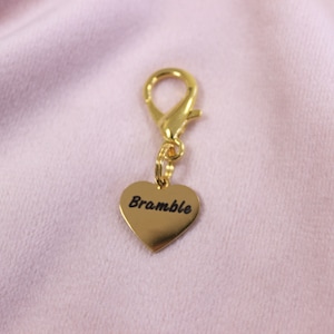 Detailed close-up of engraved horse name on polished heart charm, designed as a personalized bridle accessory.