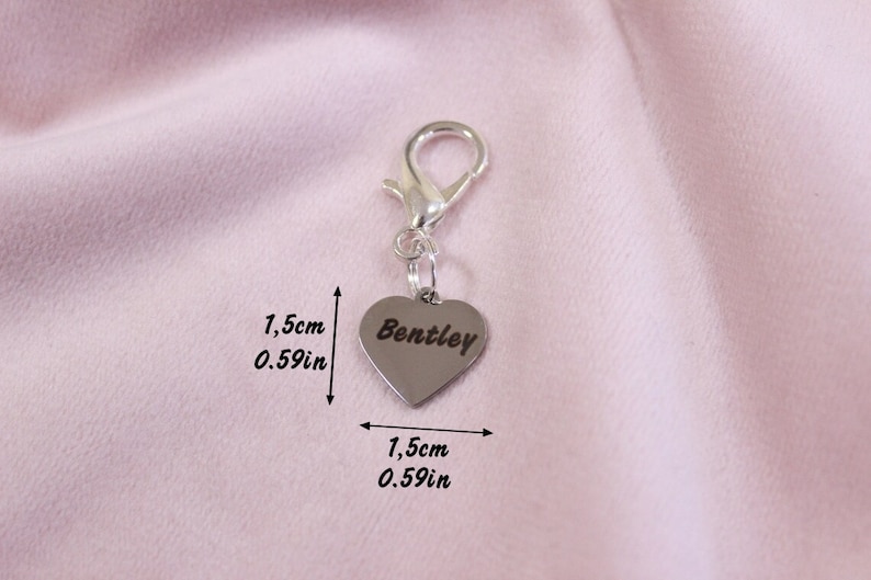 May include: A silver-toned heart-shaped charm with a lobster clasp, featuring the engraved name Bentley. The charm measures 0.59 inches in height and 0.59 inches in width, as indicated by the text and arrows visible in the image.