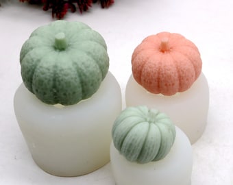 Peut inclure: Trois moules en silicone pour faire des décorations en forme de citrouille. Les moules sont blancs et les citrouilles sont vertes, orange et vert foncé.