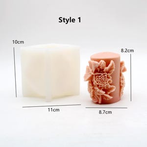 May include: A white silicone mould for making candles, with a finished candle in the shape of a cylinder with floral details. The candle is 8.2 cm tall and 8.7 cm in diameter. The mould is 10 cm tall and 11 cm wide. Style 1.