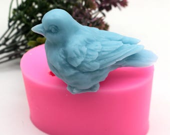 May include: A pink silicone mold shaped like a bird. The mold is designed to create a blue bird-shaped cake decoration or other edible item.