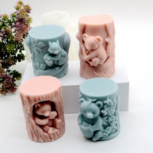 May include: Four silicone molds shaped like tree trunks with different animals inside. The molds are in two colors, light blue and light pink. The animals are a squirrel, a koala, and two bears.