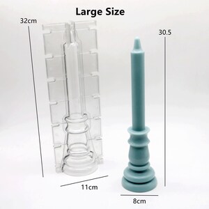 Może przedstawiać: Przezroczysty plastikowy foremka do świec z podstawą i kształtem świecy filarowej. Foremka ma 11 cm szerokości i 32 cm wysokości. Obok foremki pokazana jest niebieska świeca filarowa. Świeca ma 8 cm szerokości i 30,5 cm wysokości. Duży rozmiar.