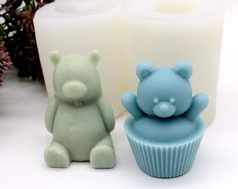 May include: Two silicone molds for making bear-shaped soaps or candles. One mold is a standing bear, the other is a bear sitting in a cupcake.