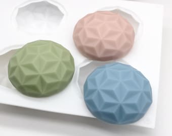 Può includere: Tre stampi in silicone di forma geometrica per la produzione di sapone o resina. Gli stampi sono in una vaschetta di silicone bianca. Gli stampi sono riempiti di resina rosa, verde e blu.