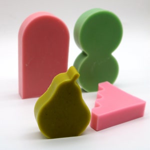 Pu&ograve; includere: Quattro forme geometriche colorate fatte di sapone. Le forme includono una pera, un rettangolo, un triangolo e un otto. La pera &egrave; verde, il rettangolo e il triangolo sono rosa e l'otto &egrave; verde.