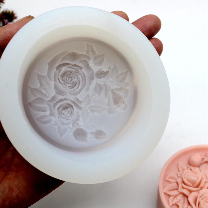 Pu&ograve; includere: Uno stampo in silicone bianco con un design in rilievo di tre rose e foglie. Lo stampo &egrave; rotondo e ha una superficie liscia.