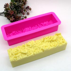May include: A pink silicone mold with a floral design, and a yellow soap bar with the same floral design.