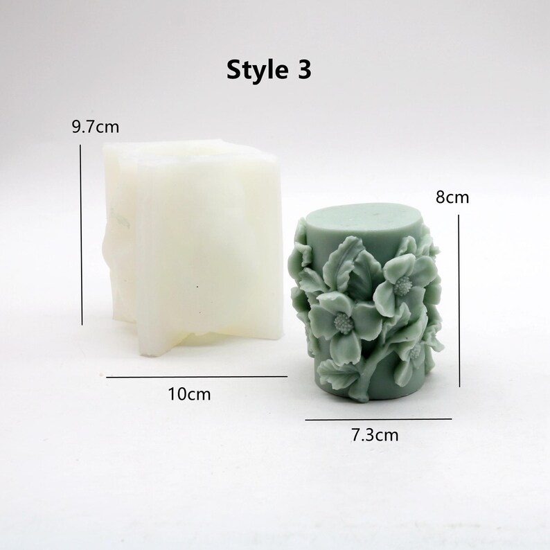 May include: Two silicone moulds for making candles. The mould on the left is a square shape with rounded edges. The mould on the right is a cylindrical shape with a floral design. The floral design is in shades of green. The moulds are labelled with measurements in centimetres. Style 3.