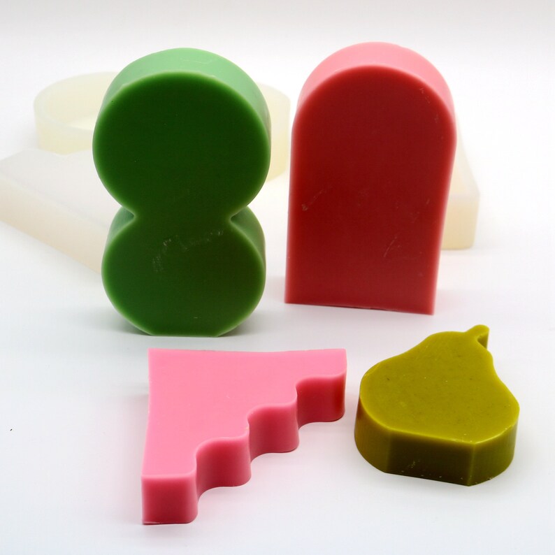 Pu&ograve; includere: Quattro saponette fatte a mano in diverse forme e colori. Un otto verde, un arco rosso, un triangolo rosa a scalare e una pera verde.