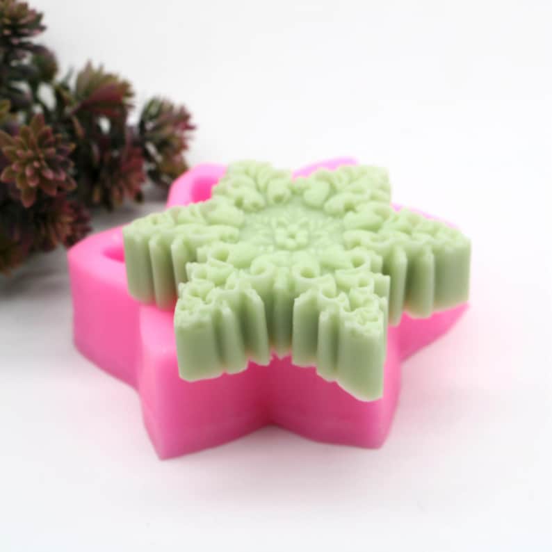 May include: A pink silicone mold shaped like a star with a green star-shaped soap inside.