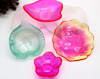 May include: Four colorful flower-shaped bowls made of clear plastic. The bowls are in shades of pink, green, and yellow.