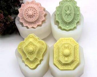 May include: Four silicone molds for making decorative soap bars. Each mold is a different shape and features a detailed design with a central starburst. The molds are white and the soap bars are pink, green, yellow, and light yellow.