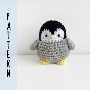 Könnte beinhalten: Ein gehäkeltes Amigurumi-Spielzeug in Form eines Pinguins mit schwarzen und weißen Gesichtszügen und gelben Füßen. Der Pinguin sitzt auf einer weißen Oberfläche.