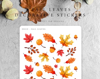 May include: A sheet of decorative stickers featuring fall leaves, acorns, and sprigs in shades of red, orange, and yellow. The text "FALL LEAVES DECORATIVE STICKERS" is at the top, with "VELVETY INK DESIGNS" below. The sheet is labeled "DECO - FALL LEAVES".