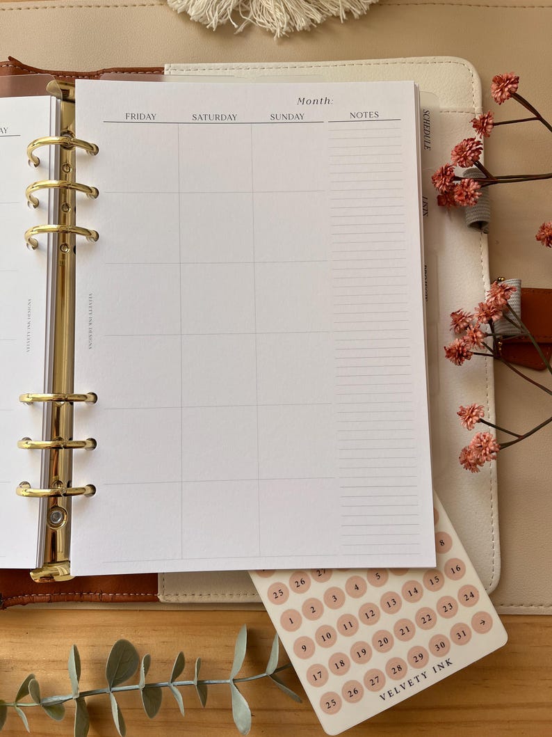 Puede incluir: Una agenda con un dise&ntilde;o de calendario semanal, con encabezados para viernes, s&aacute;bado, domingo y notas. Se incluye una hoja de pegatinas redondas con fechas. La agenda est&aacute; abierta, revelando los anillos dorados y una combinaci&oacute;n de colores neutros.