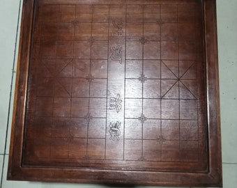 May include: A wooden game board with a dark brown finish. The board has a grid pattern with Chinese characters in the center.
