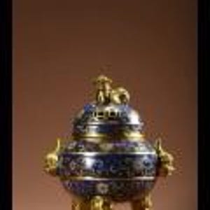 May include: A decorative, blue and gold incense burner with intricate floral patterns. The burner has a rounded body, a domed lid, and three ornate legs. The design includes gold accents and dragon-shaped handles, showcasing a detailed craftsmanship.
