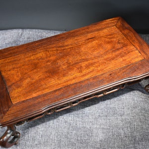 Pu&ograve; includere: Un tavolo in legno marrone scuro con un piano rettangolare e gambe intagliate. Il tavolo ha un design semplice ed &egrave; realizzato in legno massello.