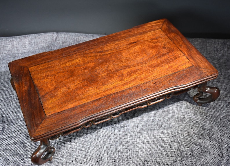 Pu&ograve; includere: Un tavolo in legno marrone scuro con un piano rettangolare e gambe intagliate. Il tavolo ha un design semplice ed &egrave; realizzato in legno massello.
