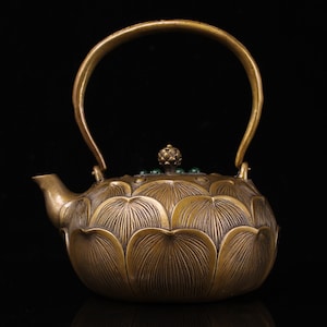 以下が含まれることがあります： 蓮の花のデザインと蓋に緑色の翡翠のノブが付いた真鍮製のティーポットです。