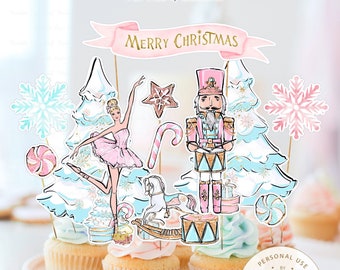 Puede incluir: Un conjunto de 17 adornos para cupcakes imprimibles con temática de Cascanueces. Los adornos incluyen una bailarina, un cascanueces, un árbol de Navidad, un bastón de caramelo, una estrella, un copo de nieve, un caballito de balancín, un tambor, una caja de regalo y un remolino de caramelo. Los adornos son de color rosa, azul y dorado. El texto "Feliz Navidad" está en una pancarta rosa.