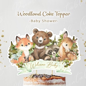 May include: Woodland themed cake topper featuring a fox, bear, raccoon, and deer with a banner that says "Welcome Baby". The topper is printed on white cardstock and is perfect for a baby shower.